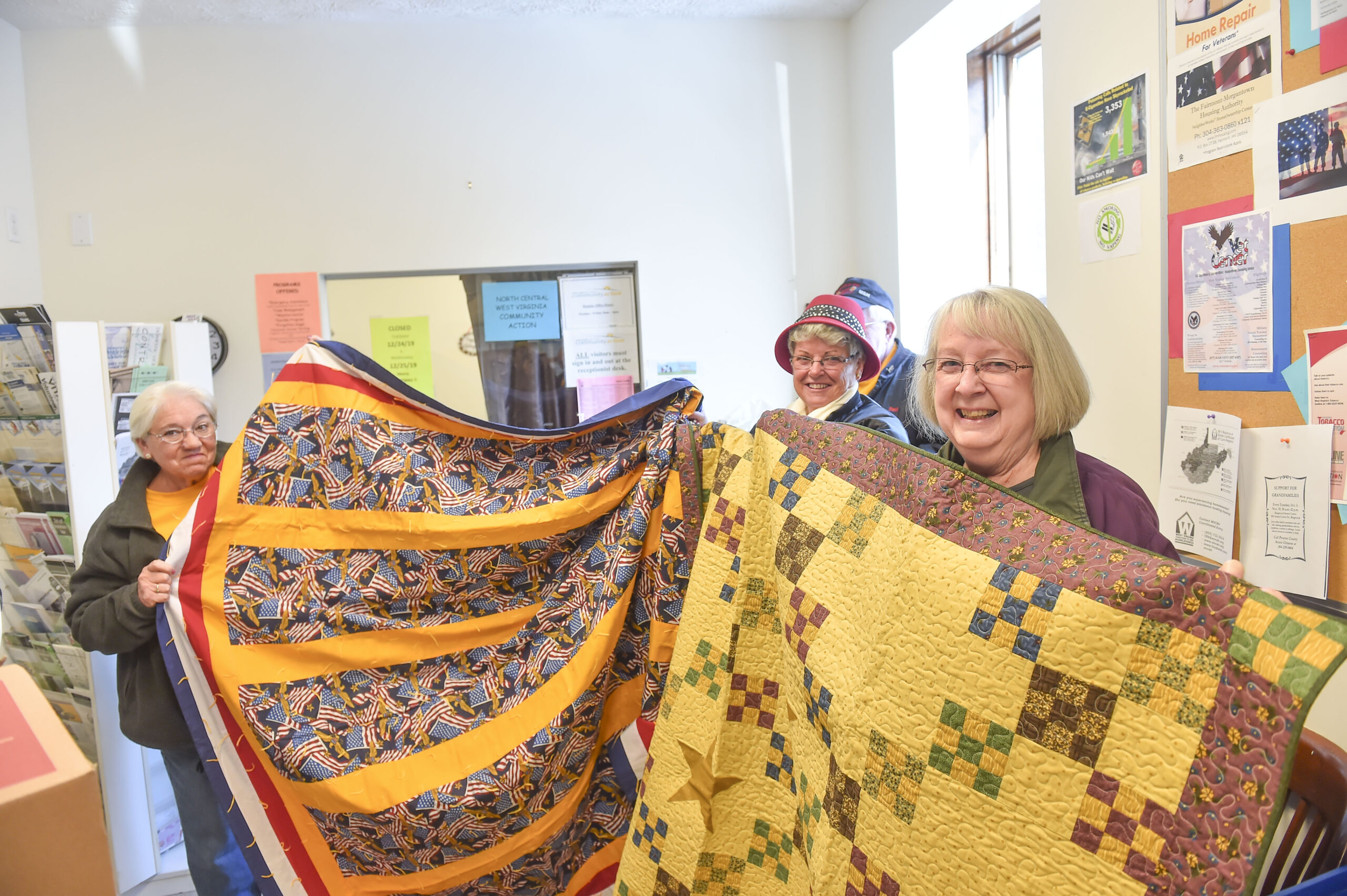 Allinda Maxon, Peggy Savage and Carolyn Miller shows the quilts that were donated to Community Action on Wednesday.