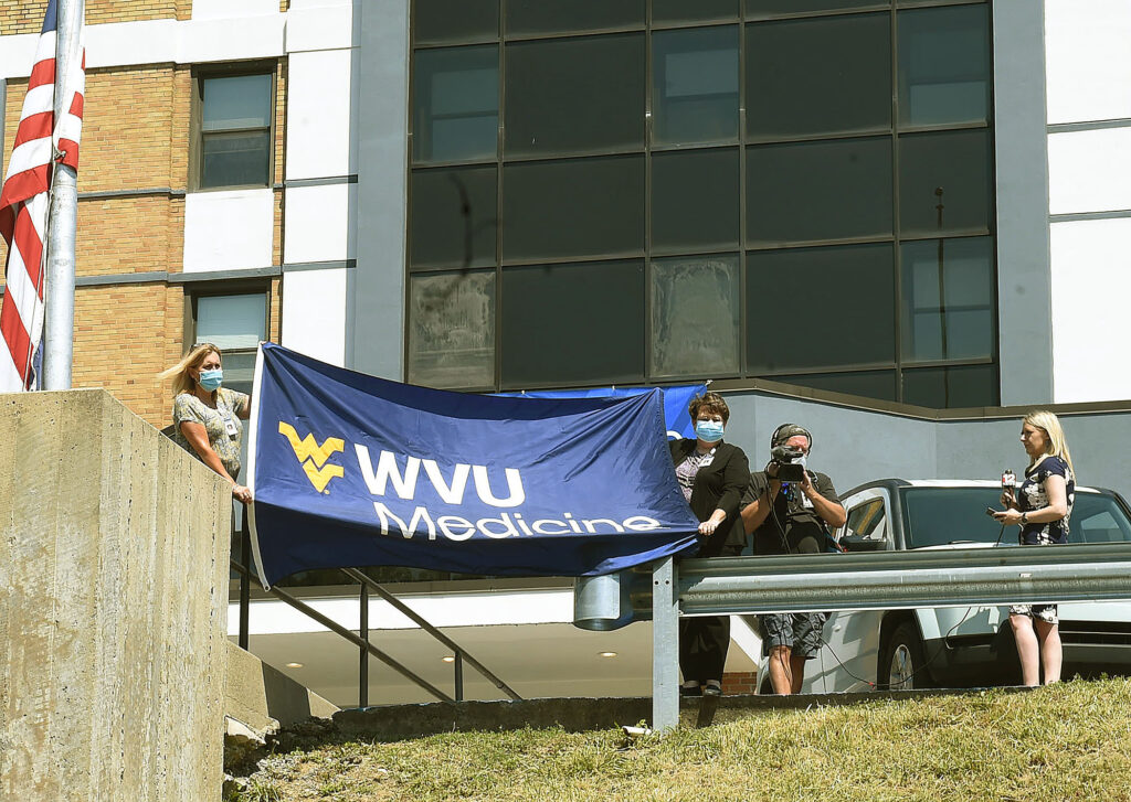 employees hold WVU Medicine flag