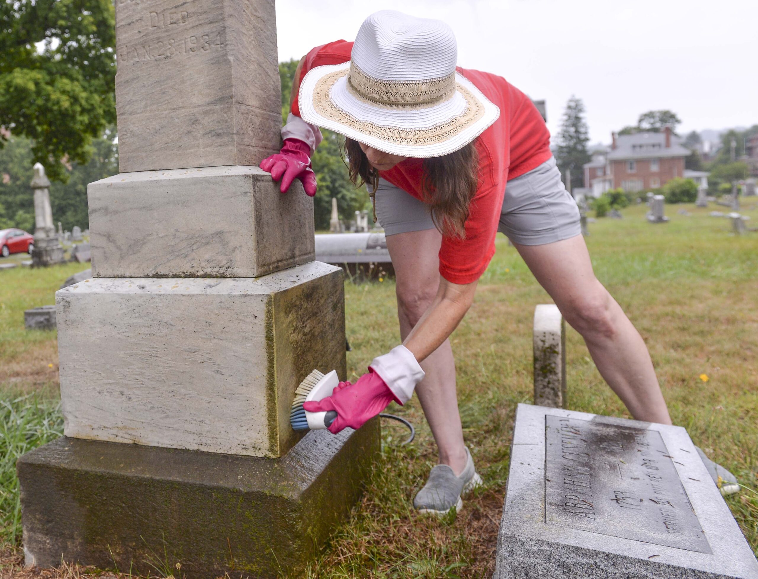 woman cleaning monument at graveyard