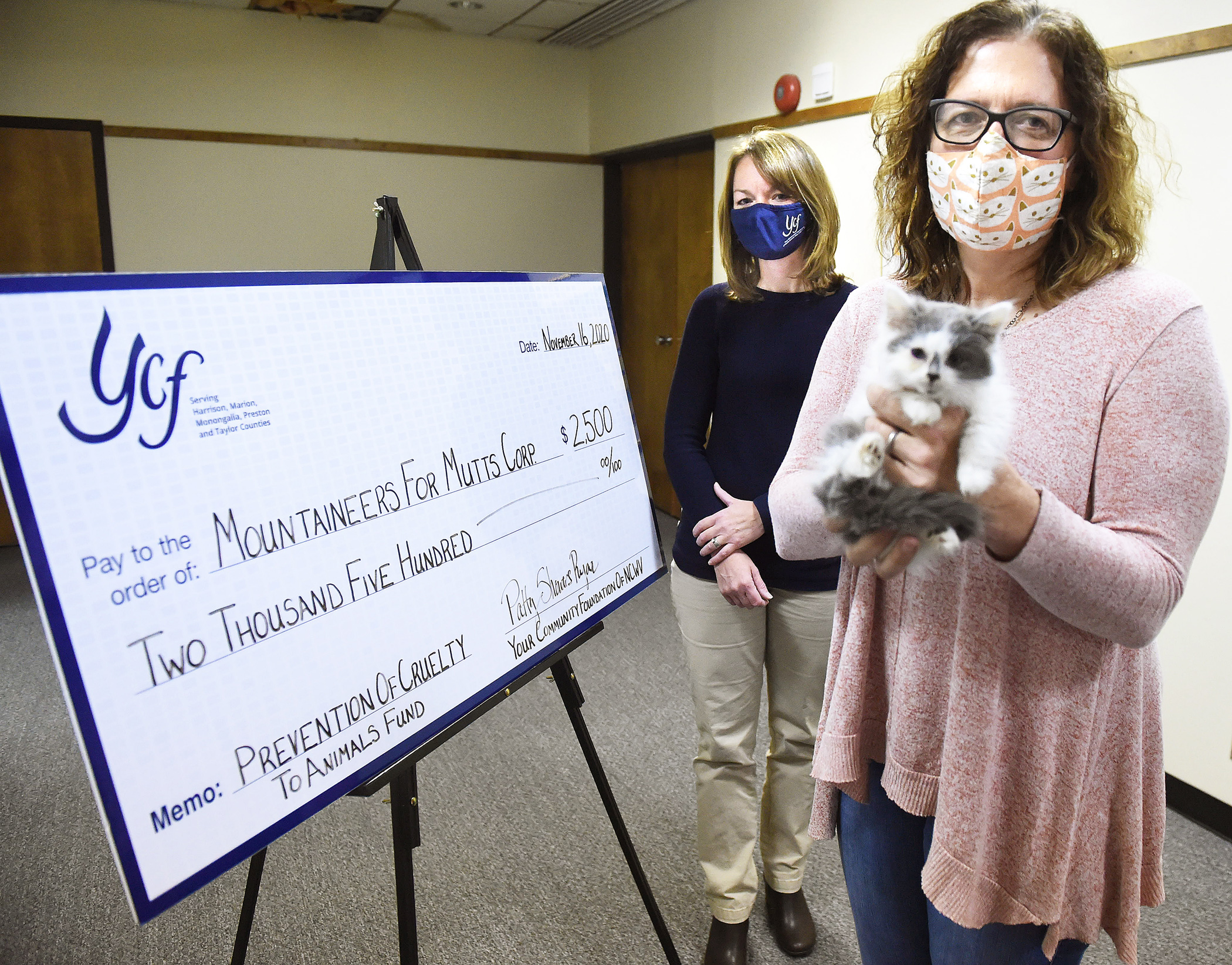 Patricia Smith holds kitten in front of novelty check